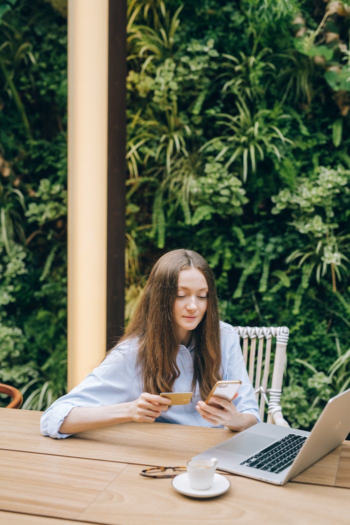 A Woman Holding Her Mobile Phone and Credit Card